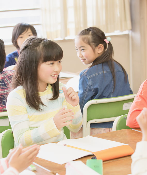 教室で笑顔で発言する児童